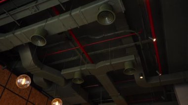 Endüstriyel bir tavanda açıkta kalan borular ve asılı ışıklarla modern ve kentsel bir tasarımı ham, tamamlanmamış bir estetik ile yakalamak..