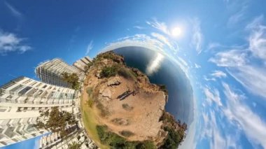 Denize bakan bir uçurumun kenarında duran bir kadın ve erkeğin küçük bir gezegen etkisi görüntüsü. Arka planda uzak dağlar ve derinliği arttıran yakınlaştırılmış bir perspektif..