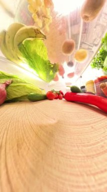 Dikey video. Dolabın içinde domatesler, biberler, salatalıklar ve soğanlar dahil olmak üzere taze sebzelerin yakın plan çekimini, dokuları ve canlı renkleri,.