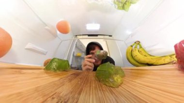 Dolly zoom buzdolabının içinde yeşil jöle yiyen bir adamı yakalar, ışık çok uzun süre sallanırken. Sahneyi kırmızı ve yeşil jöle, muz ve greyfurt çerçevesi.