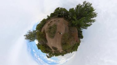 Küçük Gezegen etkisi, yeşil ağaçlar ve açık mavi gökyüzü ile çevrili bir çiftin yürüdüğü küresel bir orman manzarasını gösteriyor..