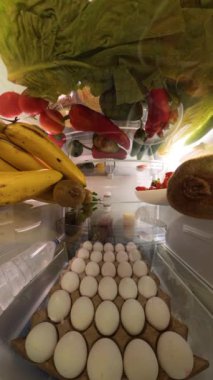 Dikey video. Buzdolabının içinden 360 derecelik küresel bir manzara yumurta, meyve ve sebzeler de dahil olmak üzere bir dizi taze ürün sergiliyor ve renkli ve daldırıcı bir mutfak perspektifi sunuyor..