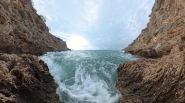 Kayalık uçurumlar arasında dalgalanan deniz suyunun yavaş çekim sahnesi, yukarıda fırtına bulutları belirdikçe kenarlarda köpüklenerek güçlü bir deniz manzarası yaratıyor..