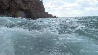 Güçlü dalgaların kayalık kayalıklara çarptığı, beyaz köpüklerin fışkırdığı ve denizin hareketinin yoğunluğunu yakaladığı yakın çekim görüntüsü..