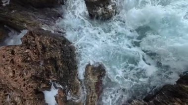 Su damlacıkları ve köpüklerin havada asılı kaldığı kayalık uçurumlara karşı dalgaların geniş açılı yavaş çekim gücü okyanusun ham enerjisini vurguluyor..