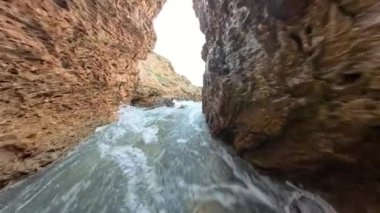 Dar kanyon benzeri bir kaya geçidinde dalgalanan suyun yavaş çekim gücü akış hareketini ve yolu çevreleyen kayalıkları vurguluyor..