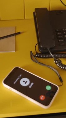 Dikey video. Sarı bir komodindeki akıllı telefonun yakın çekimi, 