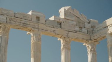Süslü detaylara sahip antik beyaz sütunların yakın çekimi, parlak, açık mavi gökyüzüne karşı klasik mimariyi sergiliyor..