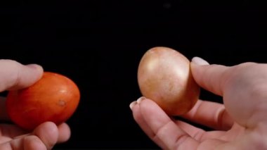 İki Paskalya yumurtasını geleneksel Paskalya yumurtası çırpma oyununda karanlık arka planda bir araya getirmeye hazır tutan eller. yavaş çekim