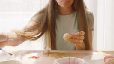 Odaklanmış bir kadın pastel renkli bir Paskalya yumurtasına ince detaylar ekliyor. Bu da karmaşık paskalya yumurtası süslemesini gösteriyor..
