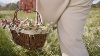 Uzun Çimenler Üzerinde Yürüyen Kadın, Çiçekler ve Paskalya Yumurtaları İçi Dolu Hasır Sepet Tutuşunun Yakın Çekimi 'nde. Yavaş çekim.