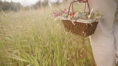 Renkli Paskalya Yumurtaları ve Çiçekleri ile Dolu Bir Sepetin Yakın Çekimi, Otlakta Yürüyen Bir Kadın gibi. Yavaş çekim.