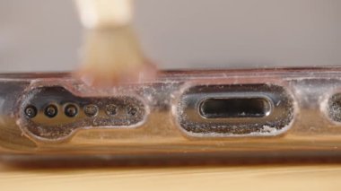 Akıllı telefonun şarj portunun yakın çekimi ve hoparlör delikleri, tozla kaplı, yumuşak bir fırçayla temizlenebilir. Toprak ve parçacıkları tamamen temizlemeyi amaçlıyor..