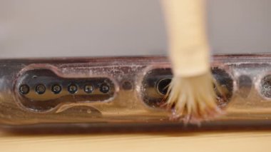 Akıllı telefon şarj portu ve hoparlör delikleri yakın çekim gösterilir, bir temizlik sırasında görünür toz ve kiri aktif olarak temizler