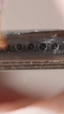 Dikey video. Toprağı ve parçacıkları temizlemeye odaklanmış, iyi bir fırçayla temizlenen tozlu siyah bir akıllı telefonun yakın plan görüntüsü.