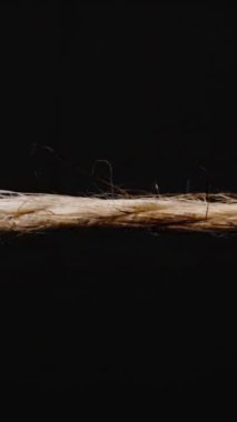 Dikey video. Görünür alevler ve kıvılcımlarla yanan bir halatın yakın plan çekimi. Isı altında kırılmaya başladığında, siyah bir arka plan üzerine kurulur.