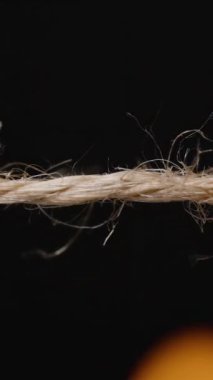 Dikey video. Bir kenevir ya da kenevir halatının yakın planında küçük alevler olan pürüzsüz bir yüzey oluşturmak için ateş tarafından yakılan lifleri ile kenevir halatı.