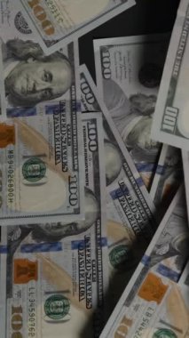 Dikey video. Yüz dolarlık banknotlar dağılır ve çerçevenin dışına uçar. Geriye sadece üçü kalır. Geriye kalan karanlık bir arka plan, azalan zenginlik ve kaybı simgeler.