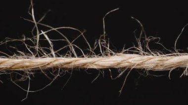 Yanan ve parçalara ayrılan bir ipe yakın plan, ısı tarafından karartılmış lifler ve arka planda parlayan közler, yıkımı ve kırılganlığı simgeliyor.