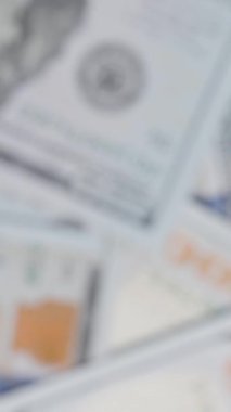 Dikey video. Döndükçe yüz dolarlık banknotlar bulanıklaşırken, Benjamin Franklin 'in portresinin net detaylarını ve para biriminin özelliklerini ortaya çıkarmak için odak kademeli olarak artıyor..