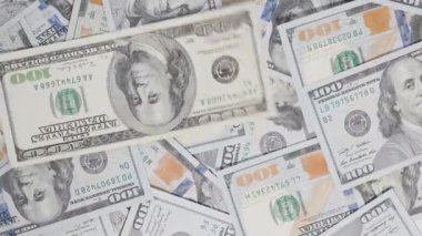 Eski yüz dolarlık banknotlar, para birimi tasarımının geçişini ve evrimini vurgulayan dönen bir hareketle yeni banknotlar yığınına atılıyor.