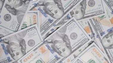 Eski yüz dolarlık banknotlar üst üste konmuş, eski ve modern tasarımların tersine dönen bir hareketle, para biriminin evrimini vurguluyor.