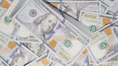 Finansal temalı bir kompozisyonda dağınık bir para biriminin üzerinde sergilenen aktif bir hareketle 100 dolarlık banknotları fırlatmak ve geri almak