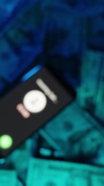 Dikey video. Amerikan para biriminin tepesinde, dramatik ve gizemli bir ses tonuyla düşük ışıkta duran bir telefonun ayrıntılı bir görüntüsü.