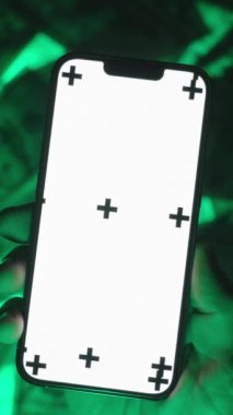 Dikey video. Boş Beyaz Ekran Modeli ve Çoklu İzleme İşaretleri ile Akıllı Telefon Kullanmanın Üst Görünümü, ABD Yüz Dolarlık Faturaların Yeşil-Parlak Arkaplanda Bir Zoom Jesti, Dijital Finans Temsilcisi
