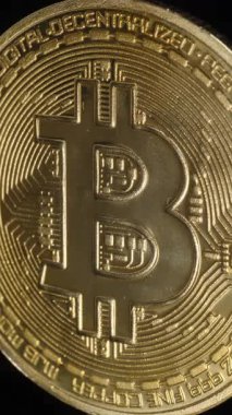 Dikey video. Bitcoin Sikkesi Siyah Arkaplan Karşısında Dik Durmakta Altın Yüzeyinde Yumuşak Işık tarafından vurgulanan Ayrıntılı Devre benzeri gravürlerle