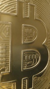 Dikey video. Bitcoin madeni parası, Altın Yüzeyi Parlak Işığı Yansıtırken Yavaşça Dönüyor. Kalın 
