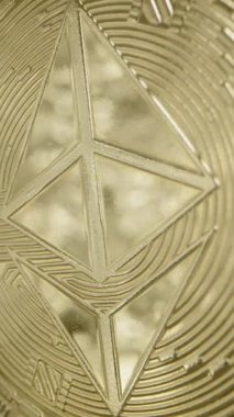 Dikey video. Parlak Altın Yüzeyli Ethereum Madeni Parlak Parıltı Pürüzsüz Bitiş boyunca kayıyor. İkonik Logo ve İşlenmiş Kalıplar Kara Arkaplan Karşısında Belirgin Görünüyor