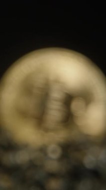 Dikey video. Bitcoin Coin yavaş yavaş Focus 'a çıkıyor, Karanlık, Dokulu Kayaların Üzerinde Duruyor. Cilalı Yüzey, Siyah Arkaplana Karşı Dijital Fosil Varlıklarını Sembolize ederek Işığı Yansıtır