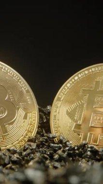Dikey video. Dokuma Taşlardan Bitcoin Madeni Paraları Toplayan İki El, Parlak Yüzeylerinden Işığı Yansıtır. Madenciliği ve Dijital Varlıkların Çıkarılmasını temsil eder