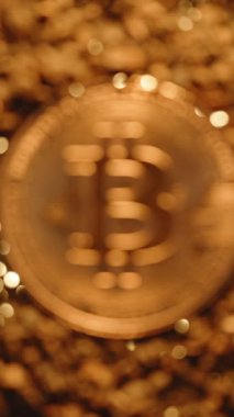 Dikey video. Görüntü 'den Görüntü' ye Çakıl Arkaplanı 'nda parlayan Bitcoin Parası, Ilık Altın Işık ile aydınlatılmış, Değeri ve Şifreleme Odağını sembolize eden