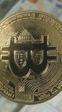 Dikey video. Bir Bitcoin Havada Zarifçe Dönüyor, Yayılmış ABD Doları Faturalarının Canlı Bir Arkaplanına Karşı Yakalandı, Kripto Para Birimi ve Mali Güç Vurgulandı
