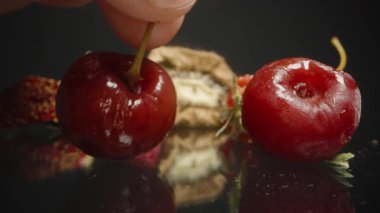 El, Yansıtıcı Siyah Yüzeyde Küçük Kurutulmuş Ahududu Kırışmış Kiraz ve Susuz Kivi 'yi Almak İçin Uzanıyor. Meyve Dokusuna ve Doğal Çürümeye Odaklan