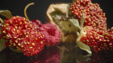 Susuz kalmış bir Kivi 'nin yakın çekimi, Kırışmış Kiraz ve Yansıtıcı Siyah Yüzeyde Tohumlu Kurutulmuş Çilek. Meyve Dokusuna ve Yaşlanma Detaylarına Odaklan