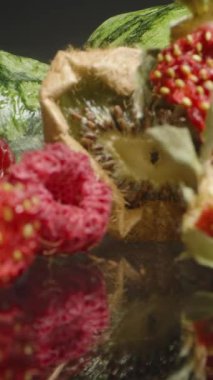 Dikey video. Kurumuş Kivi ve Yansıtıcı Siyah Yüzeyde Tohumlu Çoklu Kurutulmuş Çilek. Yaşlanma, Kırışık Cilt ve Doğal Kurutma Sürecine Vurgu