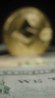 Dikey video. Ethereum Coin in in Soft Focus, bir yığın ABD Doları Faturası üzerine kurulmuştur. Dijital ve Geleneksel Para Birimlerinin Kesişiminin Vurgulanması