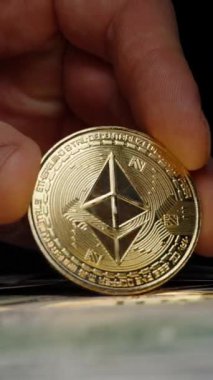 Dikey video. Bir yığın Amerikan Doları 'nın üzerinde Altın Ethereum madeni para tutuyor. Geleneksel Para Birimi için Kripto Para Takasını Sembolize Etmek