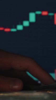 Dikey video. Arka planda Yükselen Piyasa Eğilimlerini Gösteren Ticari Çizelge ile Bitcoin Sikkesi yakınındaki Masada Dolar Faturaları Toplama