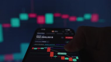 Bitcoin Ticaret Uygulamasını Yeşil ve Kırmızı Şamdanlarla Gösteren Akıllı Telefon, Finansal Piyasa Eğilimleri ve Kripto Para Çizelgeleri 'nin bulanık geçmişine Karşı El Tutma Aygıtı,