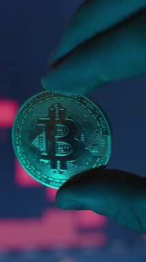 Dikey video. Yakınlaştır. Düşen Çizelgedeki Kırmızı Şamdanların Bulanık Arkaplanına Karşı El Altında Bitcoin Bozukluğu Kripto Para Düşüşü ve Finansal Kayıp Konseptini Vurguluyor