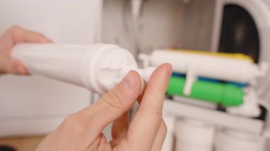 Eller Tutma ve Hassas Bir Beyaz Filtre Elementi Ayarlama, Çok Renkli Ters Osmosis Tüpleri Arka planda Görünür, Yükleme Sürecini Vurguluyor