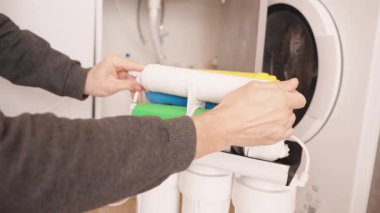 Beyaz filtre elementi ile Osmosis Sistemi Tersine Osmosis Suyu Şeffaf bir kabın içine dökerek, Bir Filtreleme Biriminin Değiştirme Süreci sırasında Sıvı Akımını Gösterir