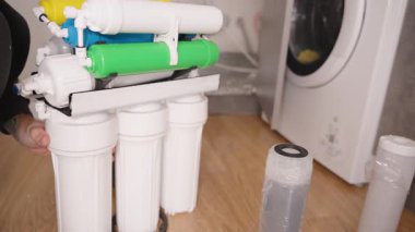 Eller Osmosis Sistemi 'nin Filtre Konutlandırma Ampulünü sökmek için Bir Anahtarı Kullanıyor, Bakım Sürecinin bir parçası olarak İçerideki Filtreyi Değiştirmeye Hazırlanıyor