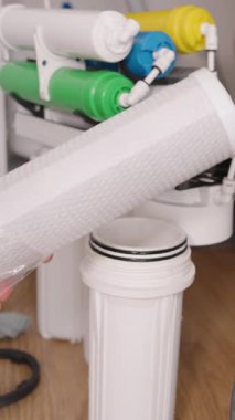 Dikey video. Yeni bir filtre kartuşunu Tersine Osmosis Sistemi 'ne yerleştirmek ve yerleştirmek için Eller Açılıyor ve Hazırlanıyor, Gelişmiş Su Filtreleme İçin Değiştirme Sürecini Vurguluyor