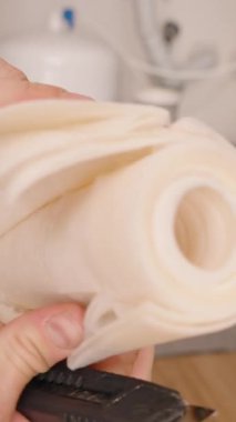 Dikey video. Eller Kesik Açılmış Kağıt Filtresinin Katmanlarını Tersine Osmosis Sistemi 'nden Geri Çekerek Zaman İçinde Tuzağa düşürülen İç Yapı ve Kirleticileri Açığa Çıkarıyor