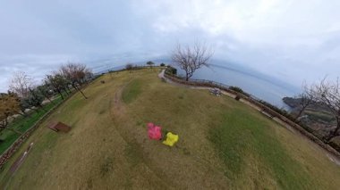 Pembe Yağmurluk Giyen Bir Adam ve Sarı Yağmurluk Giyen Bir Kadın Bulutlu Bir Gün 'de Deniz Kenarı Bir Parkta Yürüyor